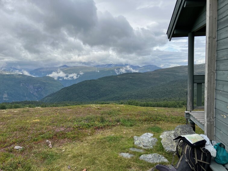 Mountain view, backpack next to side of wooden hut