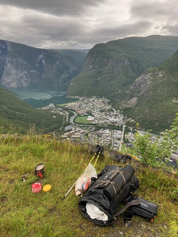 Looking down at Ovre Årdal from around 600m, backpack and kitchen on a small grassy plateau in the foreground