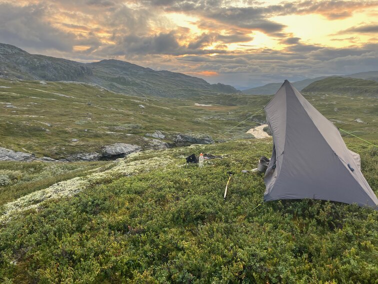 Tent on small hill with dramatic sunset